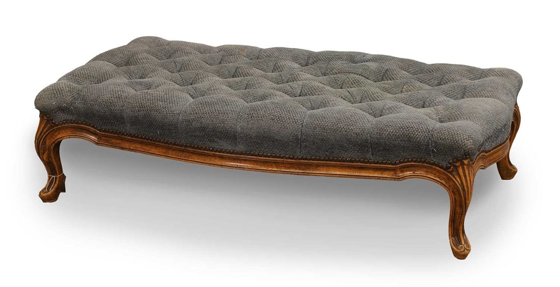 An upholstered footstool, 20th century, French,: An upholstered footstool, 20th century, French, upholstery in a blue textured fabric with a carved frame terminating on squat cabriole legs 116cm wide, 65cm deep, 30cm high Condition Report: Some