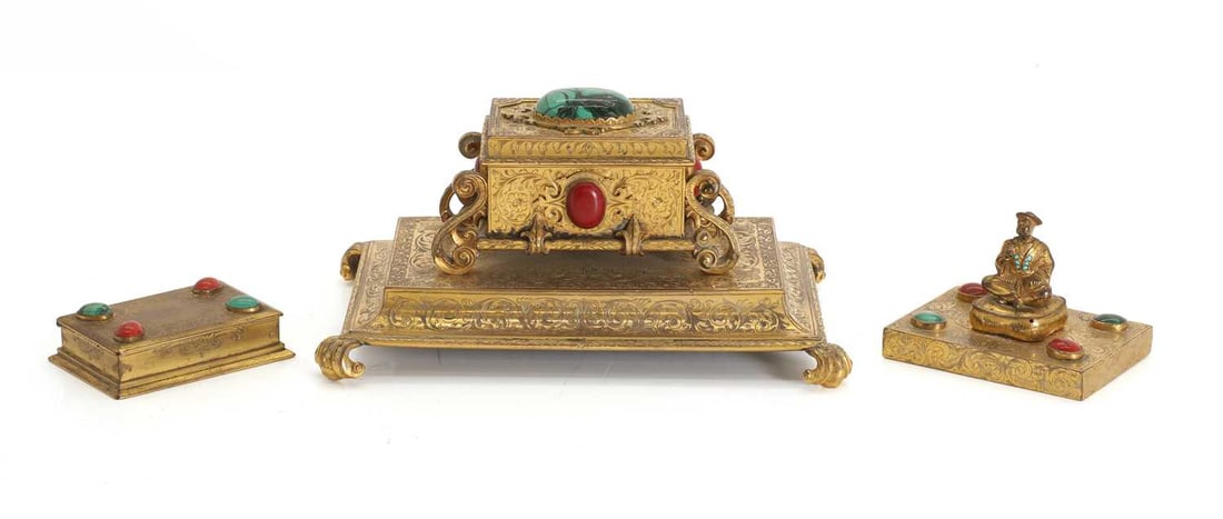 A chinoiserie decorated brass desk set, 19th century,: A chinoiserie decorated brass desk set, 19th century, comprising an inkwell, paperweight and pot, all with etched floral design and the paperweight with seat figure to the top, all inlaid with cabocho