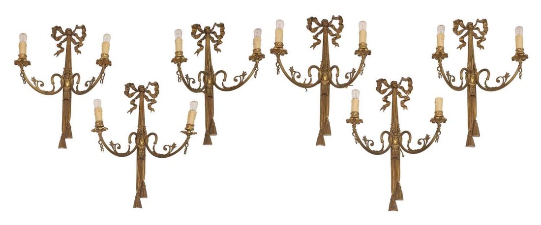 A set of six gilt brass wall appliques, early 20th century,: A set of six gilt brass wall appliques, early 20th century, all with twin branches decorated with moulded ribbon swags and foliate details terminating in electirfied faux candles 37cm wide, 56cm high 