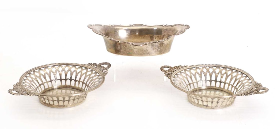A pair of silver bon bon dishes,: A pair of silver bon bon dishes, of circular form with twin handles, by W E L? , London, 1904, together with an ovoid example by William Hutton and Sons, Birmingham, 1901 15.5cm wide 10.29ozt 3