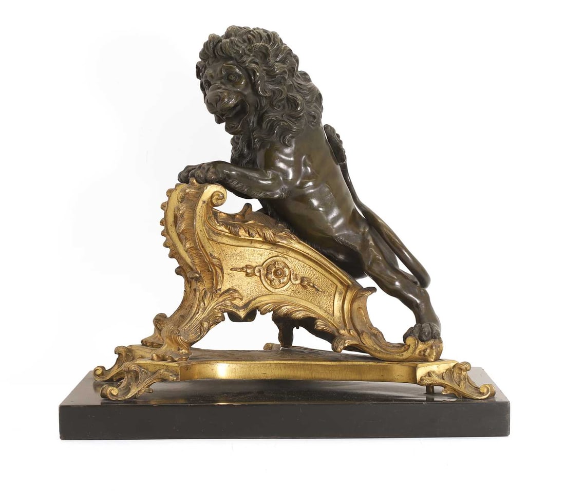 A gilt and patinated bronze animalier chenet, 19th century,: A gilt and patinated bronze animalier chenet, 19th century, modelled as a lion on a scrolled base, terminating on a wooden base 44cm wide, 24cm deep, 43cm high Condition Report: Some fading and
