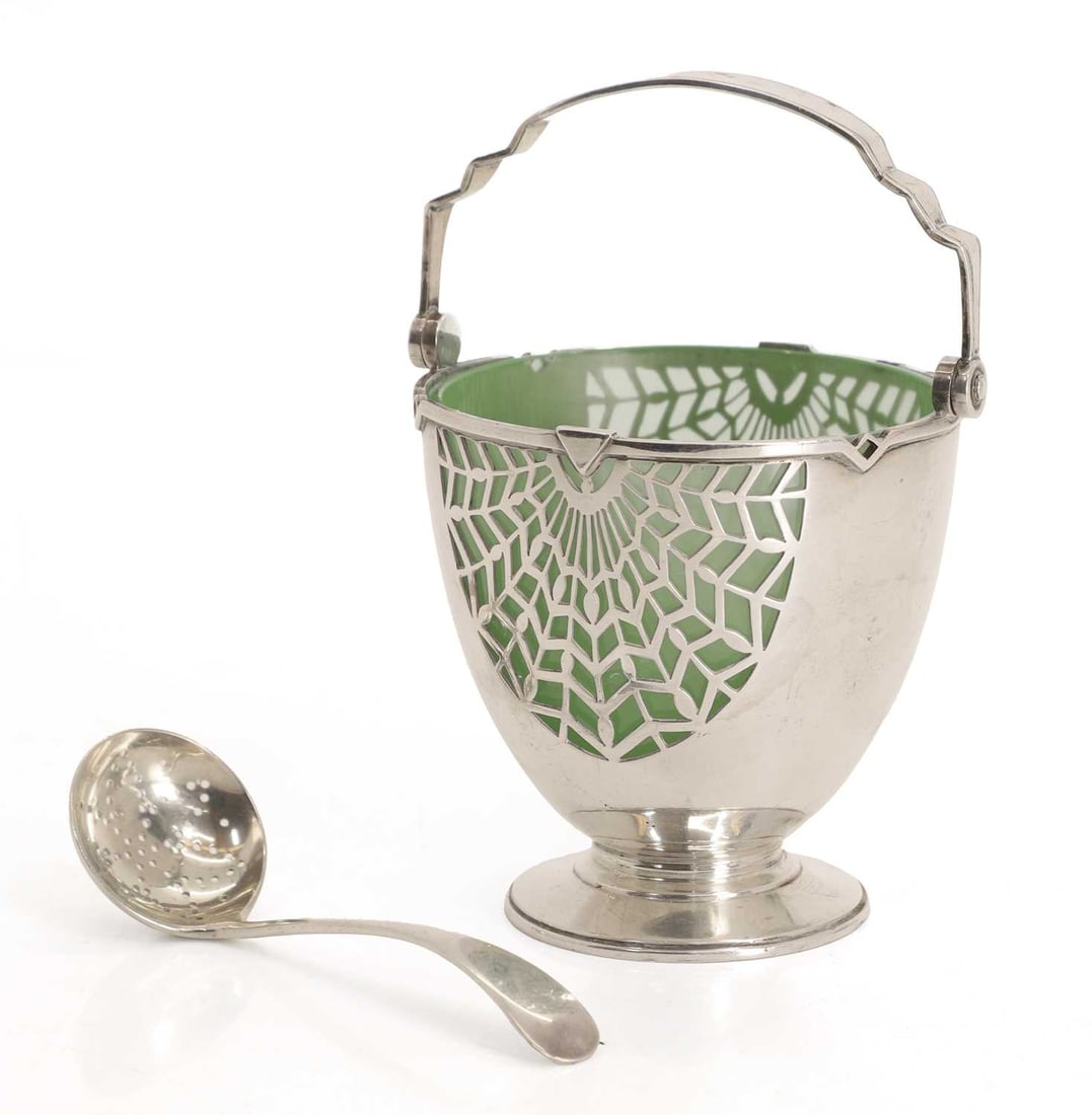 A silver ladled basket with pierced spoon,: A silver ladled basket with pierced spoon, by Mappin & Webb, Sheffield, 1936, with green glass liner, the sides of the bucket with pierced web decoration, shaped handle and matching sugar spoon