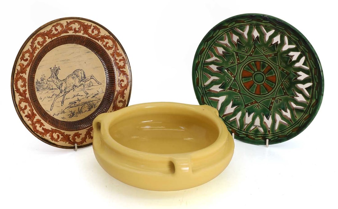 A pottery plate, in the manner of Hannah Barlow, late 19th century,: A pottery plate, in the manner of Hannah Barlow, late 19th century, incised with a running doe, within a spiking leaf border, indistinct marks, a pierced pottery green glazed dish, and a Rookwood