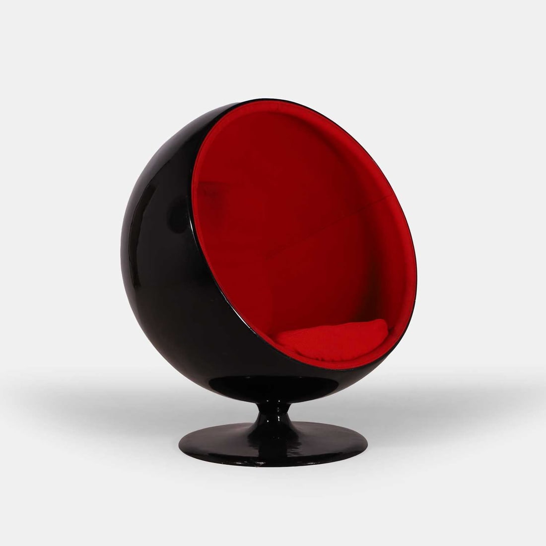 After Eero Aarnio, a 'Ball' chair,: After Eero Aarnio, a 'Ball' chair, originally designed in 1963, the black fibreglass ball on a black aluminium base, with red upholstery and matching cushions 99cm wide, 99cm deep, 130cm high, 43cm