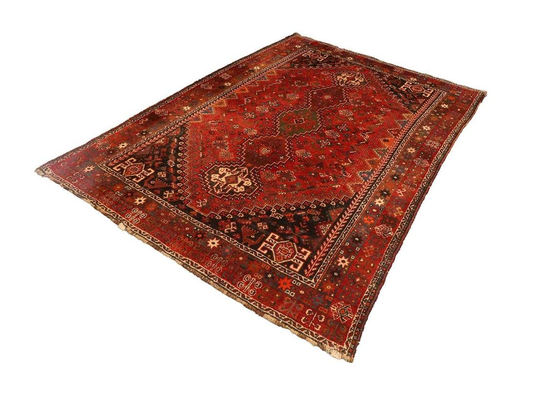 A hand knotted Shiraz on a red ground,: A hand knotted Shiraz on a red ground, with five central medallions on a decorated field featuring peacocks, camels and birds 311cm long, 219cm wide Condition Report: Some sun fading, with repairs to 