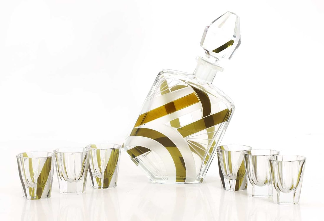 An Art Deco liqueur set, circa 1930,: An Art Deco liqueur set, circa 1930, in the manner of Karel Palda, comprising a decanter and six liqueur glasses, cut, flashed, and engraved glass decanter 14.5cm wide, 6cm deep, 23.5cm high, glasses