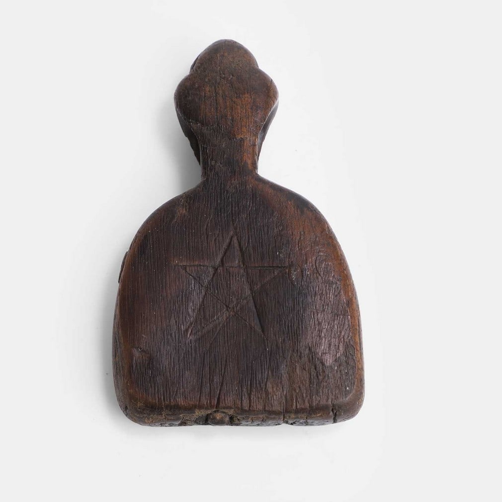 An oak animal charm, 19th century,: An oak animal charm, 19th century, of flattened bell form, with a carved pentagram symbol and other marks, with a hole for suspension (7cm wide, 2.3cm deep, 11.5cm high) Footnote: These are believed t