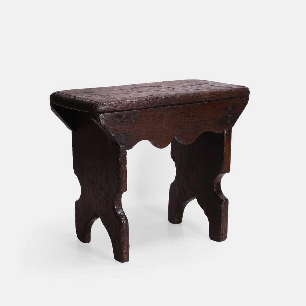 An oak stool, probably 19th century, incorporating earlier timbers,: An oak stool, probably 19th century, incorporating earlier timbers, with a hexafoil apotropaic or witch mark carved to the seat (44.5cm wide, 21.5cm deep, 36.5cm high) Footnote: A hexafoil (also known