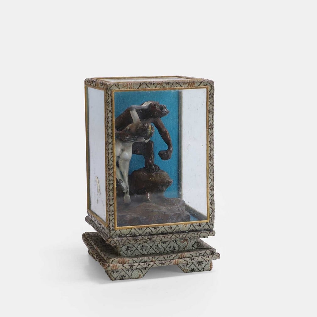 A cold-painted lead figure of a gorilla holding a naked woman, circa 1920s,: A cold-painted lead figure of a gorilla holding a naked woman, circa 1920s, in a Japanese-inspired embroidered glass box (7.7cm wide, 7.2cm deep, 12.5cm high) Condition Report: Some chips to cold pain