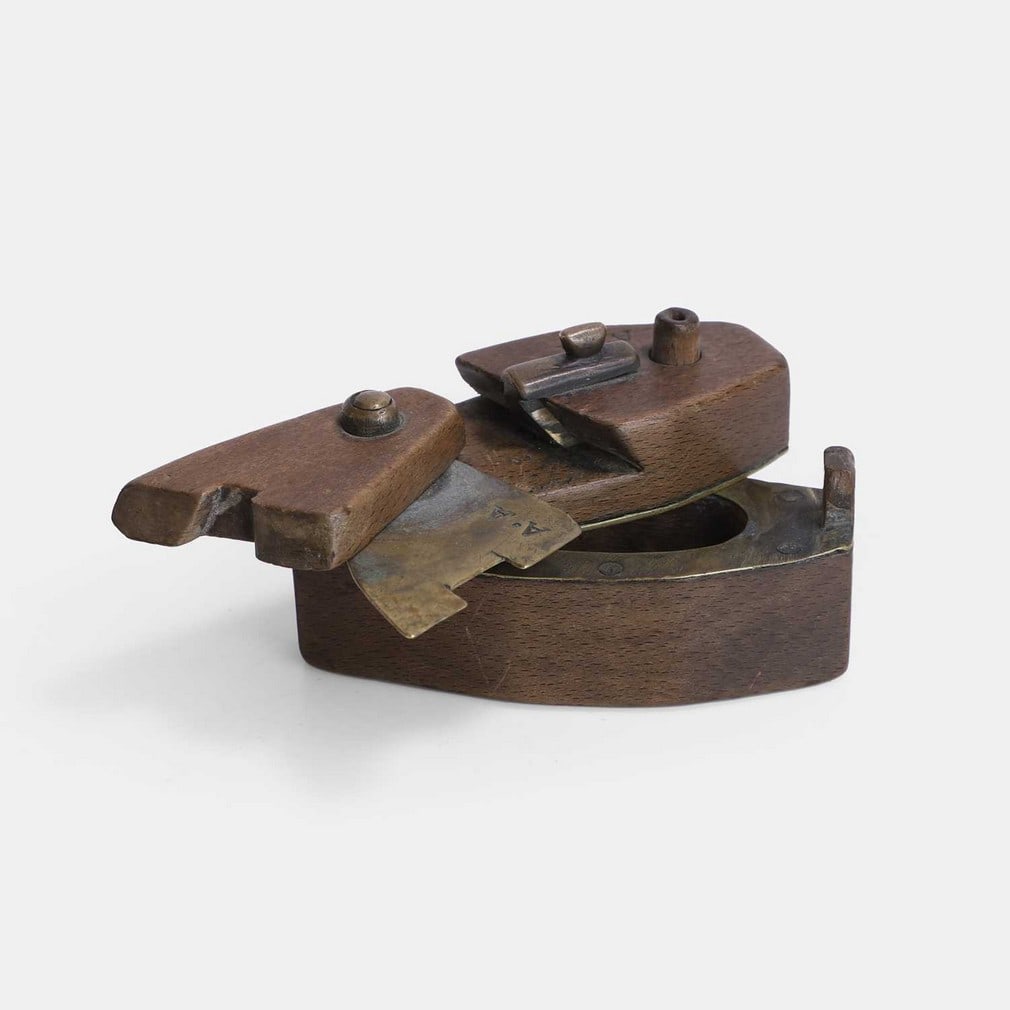 An ‘impossible’ puzzle lock snuffbox, 19th century,: An ‘impossible’ puzzle lock snuffbox, 19th century, coffin-shaped, wooden and brass with various buttons and levers, carved initials reading 'AA' in three places on the box (9.5cm wide, 3.