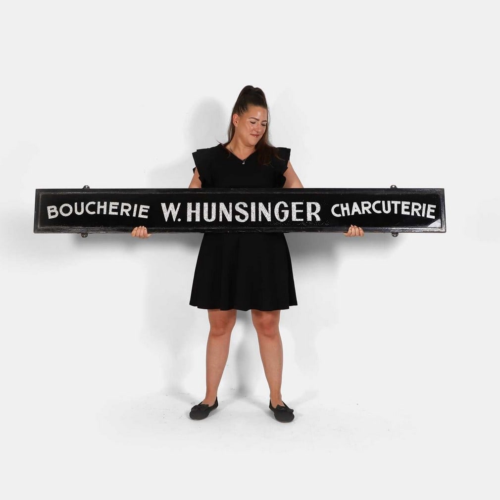 A French glass 'Boucherie' trade sign, circa 1930s,: A French glass 'Boucherie' trade sign, circa 1930s, reverse-painted in silver crinkled foil on black glass, with arched lettering, 'Boucherie' and 'Charcuterie', with 'W Hunsinger' between, one-sided,