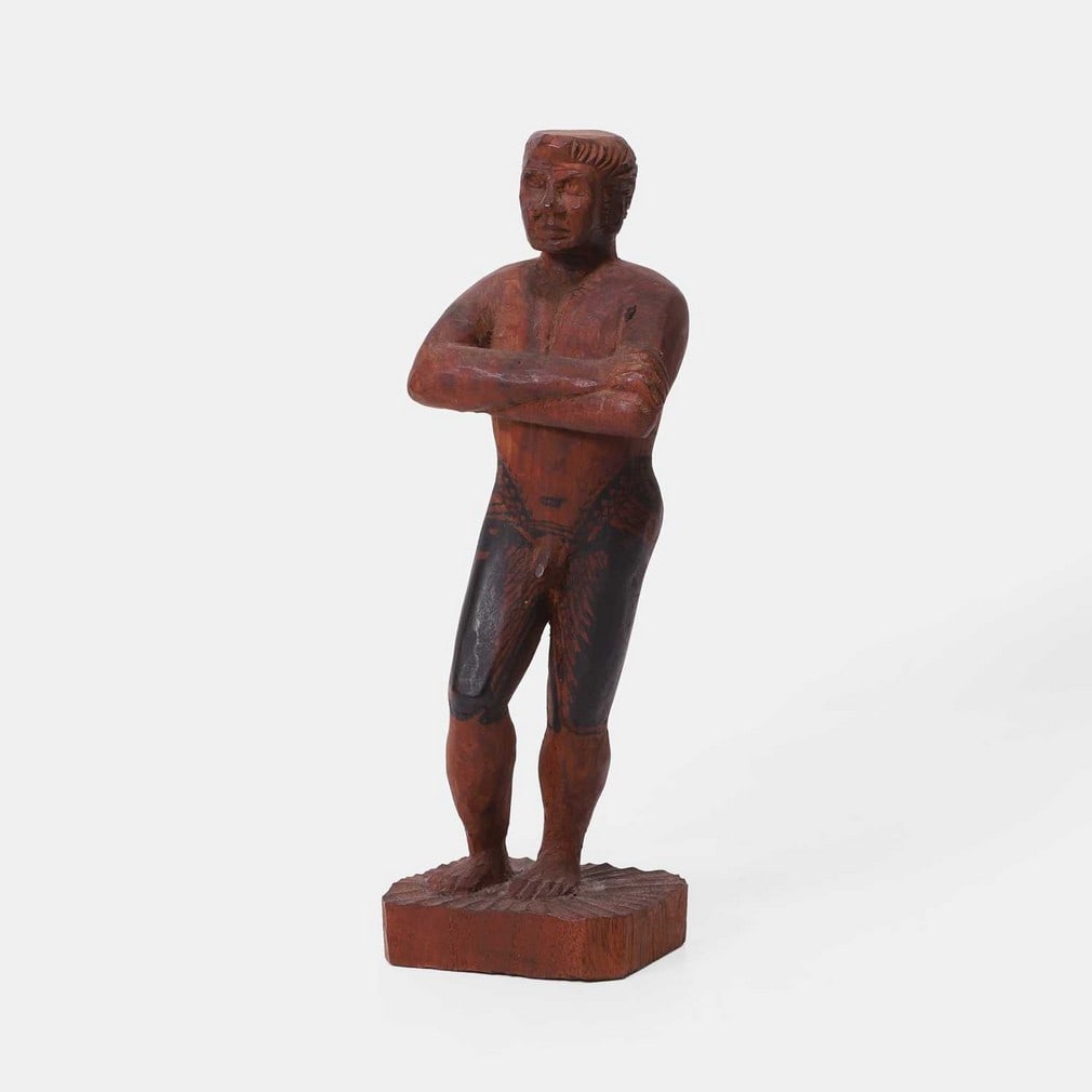 A carved wood figure of a tattooed Samoan, early 20th century,: A carved wood figure of a tattooed Samoan, early 20th century, standing nude, with his armed crossed, with tattoos on his buttocks and thighs, probably used as a guide/model for Samoan tattoo artists