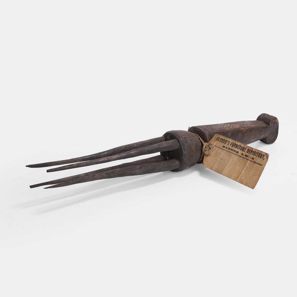 A Fijian cannibal fork, 20th century,: A Fijian cannibal fork, 20th century, with a geometric carved wooden handle and four tapered tines, with a 'Harrod’s Furniture Depository' label (33.5cm long) Condition Report: The four points o
