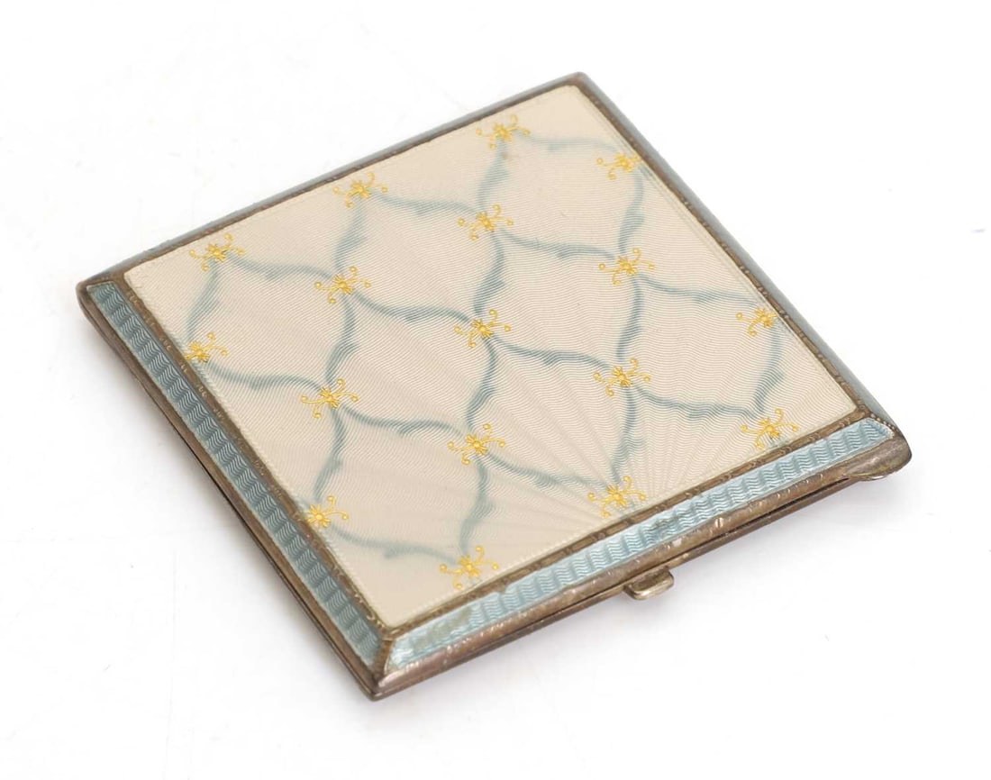 A silver and enamelled ladies powder compact, 20th century,: A silver and enamelled ladies powder compact, 20th century, with a latticed design, with canted edges and engine-turned, the interior with a mirror and a powder puff, with an associated box 6.5cm