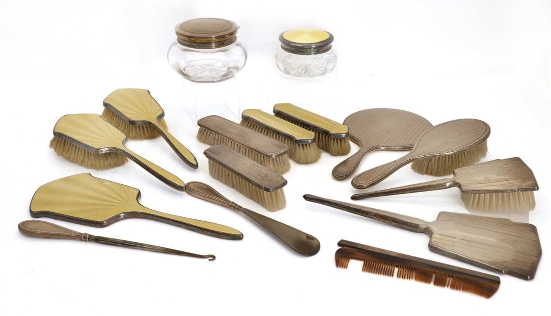 Two silver-mounted dressing table sets, 20th century,: Two silver-mounted dressing table sets, 20th century, one engraved silver, with six pieces, including a button hook and shoe horn, and a mounted glass bowl, a silver and yellow enamelled set, six piec