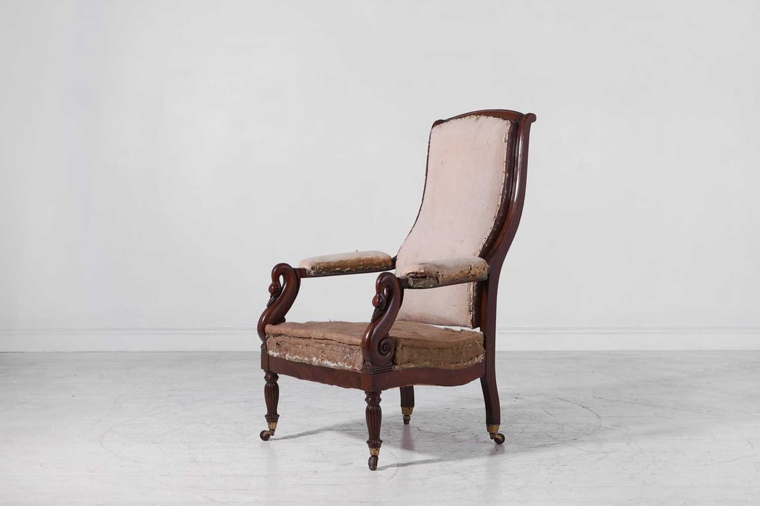 A Louis Philippe mahogany armchair, circa 1840, French,: A Louis Philippe mahogany armchair, circa 1840, French, with a tall curved back above a pair of open arms with swan terminals, raised on lobed baluster supports terminating in ceramic castors 61cm
