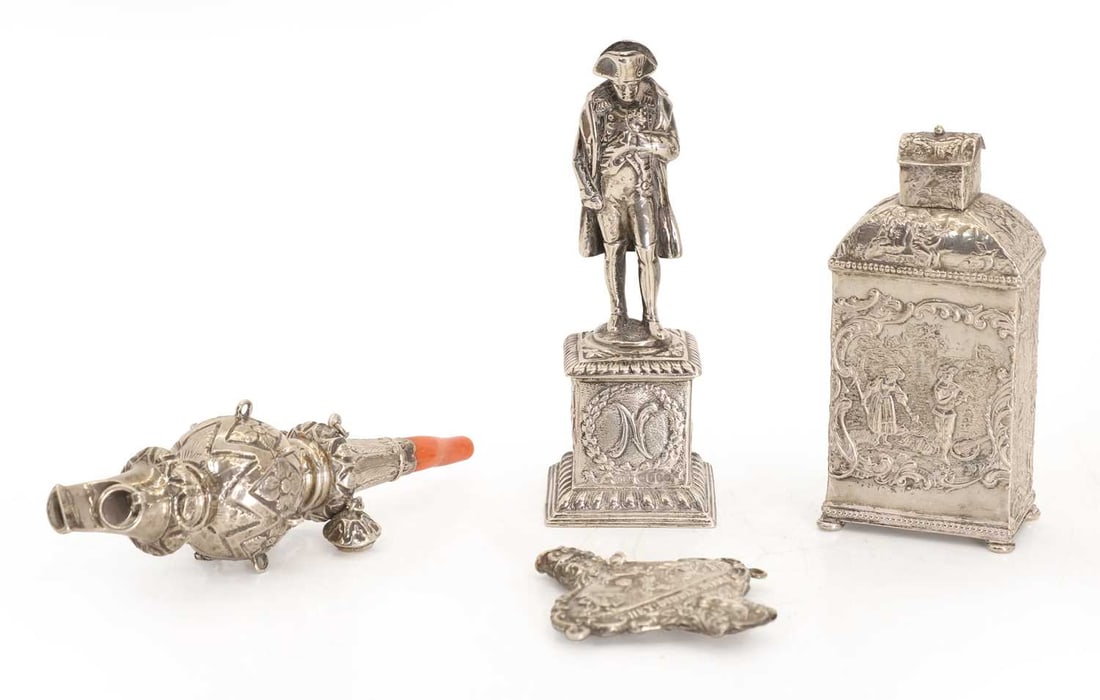 A silver baby rattle,: A silver baby rattle, etched 'Gilbert June 28 1867' together with a white metal tea cannister, detailed with scenes with dogs, a man playing the lute etc, a silverplated Napoleon paperweight and one o