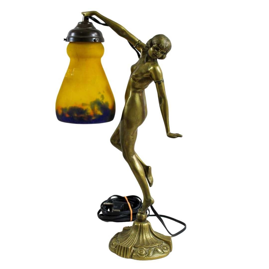 A Muller Frères Art Nouveau figural table lamp, circa 1930,: A Muller Frères Art Nouveau figural table lamp, circa 1930, depicting a posing figure upon a ball, holding a lamp, marked to the glass 40.5cm high