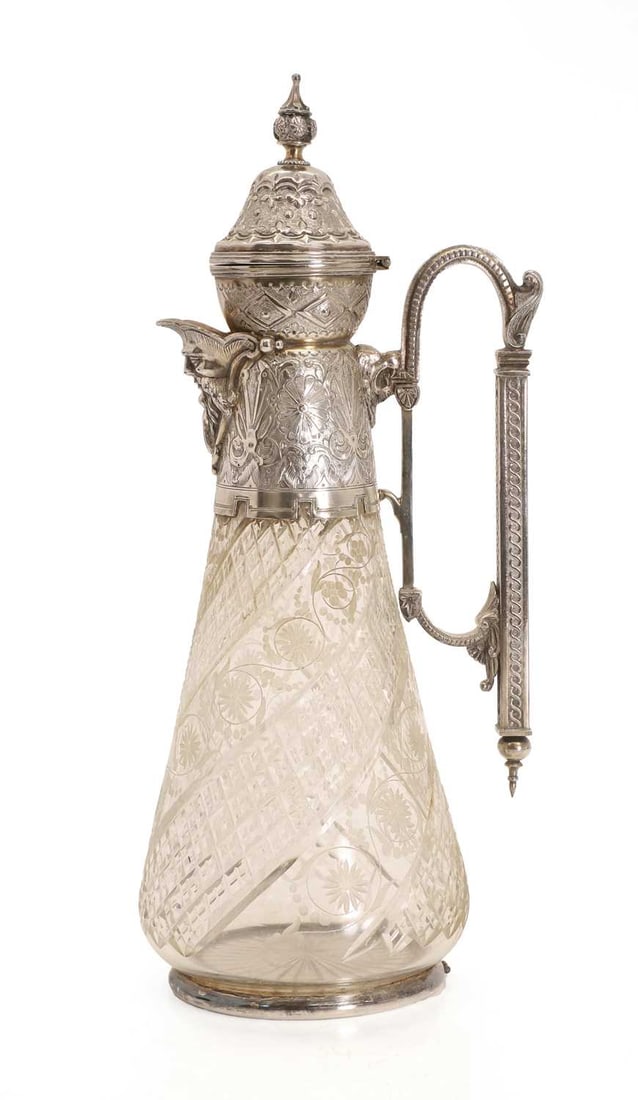 A glass and silver plated claret jug, 19th century,: A glass and silver plated claret jug, 19th century, with mask spout and the mount with floral and scrolled design terminating in an angular handle with cut glass base 15cm wide, 36cm high