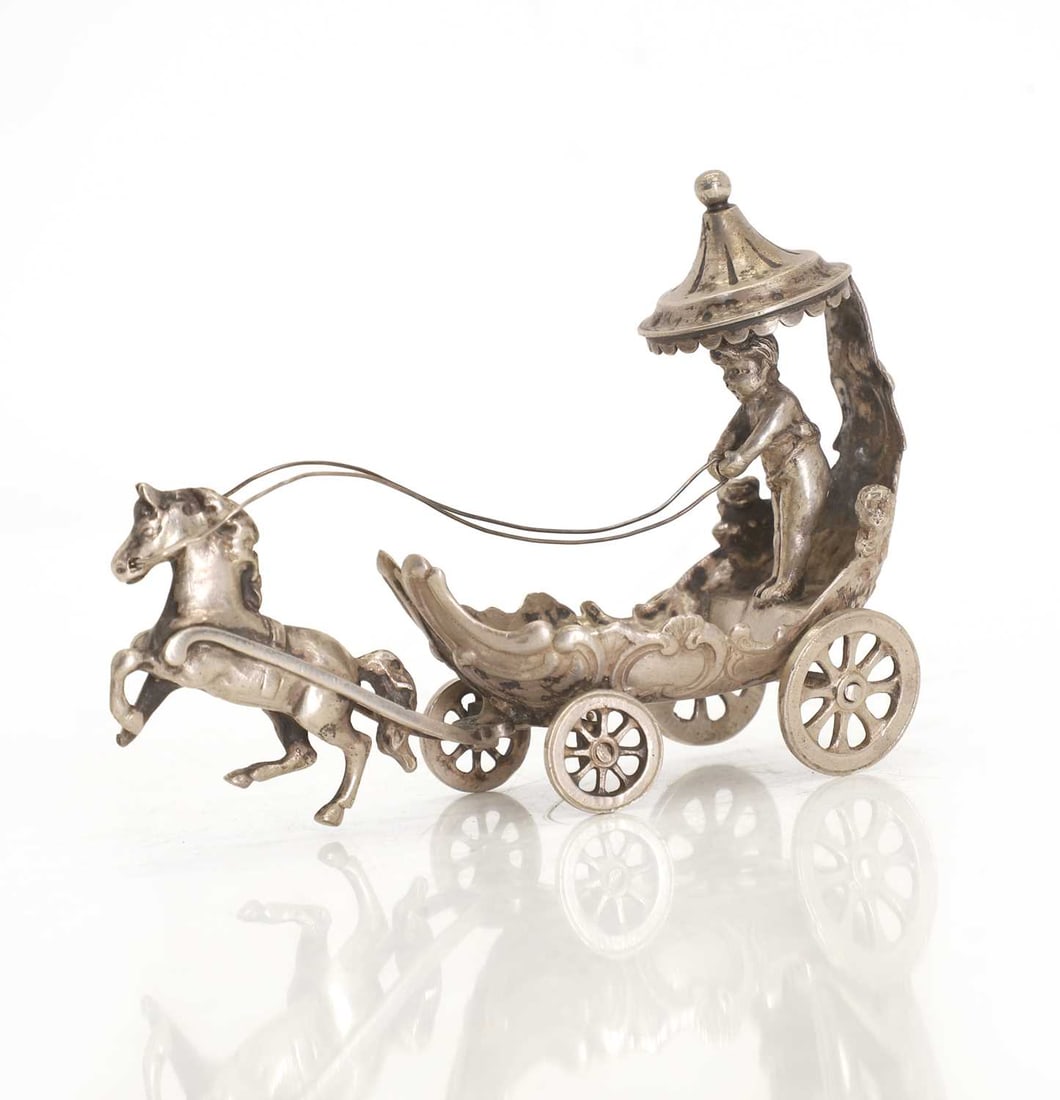 A silver figural salt cellar, early 20th century, German: A silver figural salt cellar, early 20th century, German modelled as a putto driving a chariot, 800 silver, marked Gebrüder Neumann, Hanau 11cm long, 8cm high, 2.5ozt