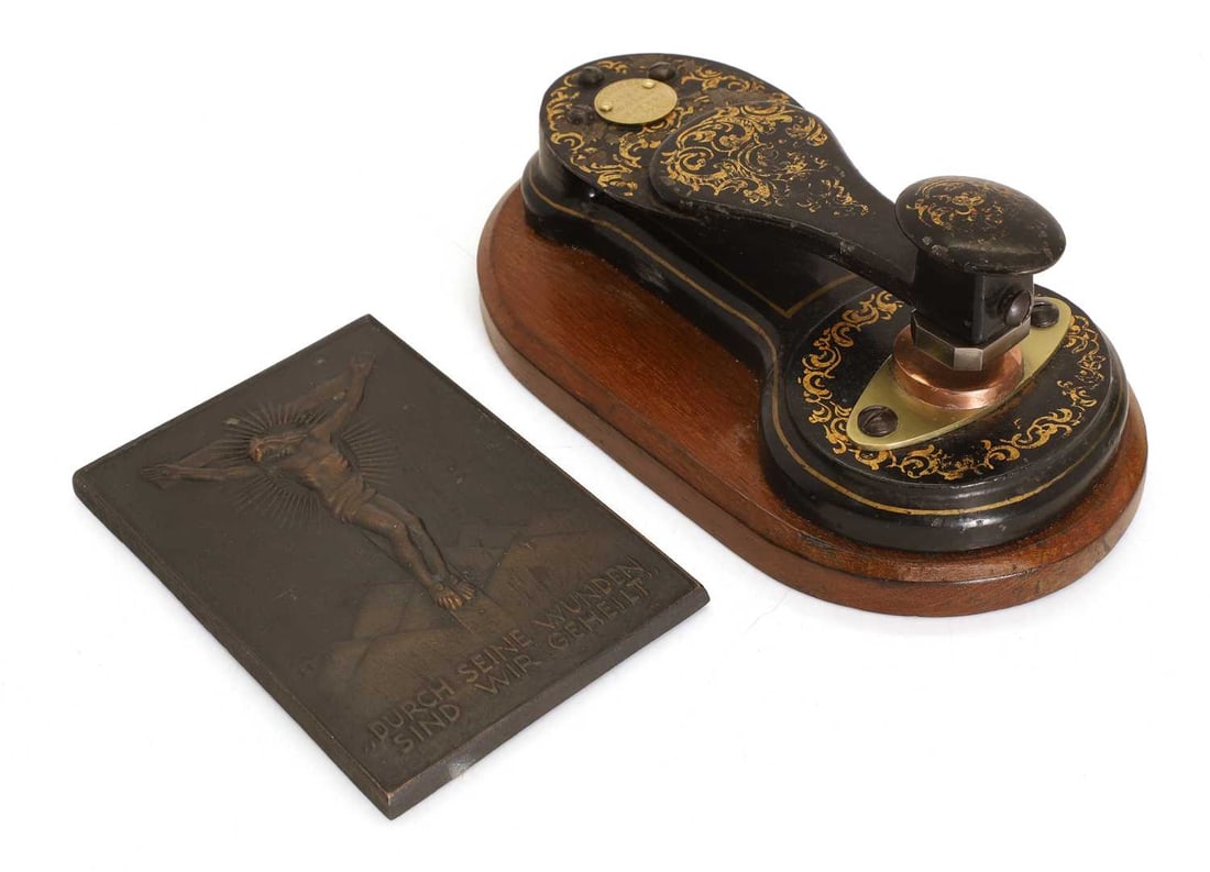 A patent seal punch by Sampson Mordan & Co, London,: A patent seal punch by Sampson Mordan & Co, London, with gilt decoration and a maker's plaque on a mahogany base, and a German religious plaque, a Crucifix, by Heinrich Moshage stamp 20cm long, plaque