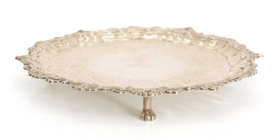 A silver salver,: A silver salver, by William Peaston, London, 1749, with relief shell moulded rim and cypher to the central field, terminating on lion paw feet 22cm diameter, 13.4ozt