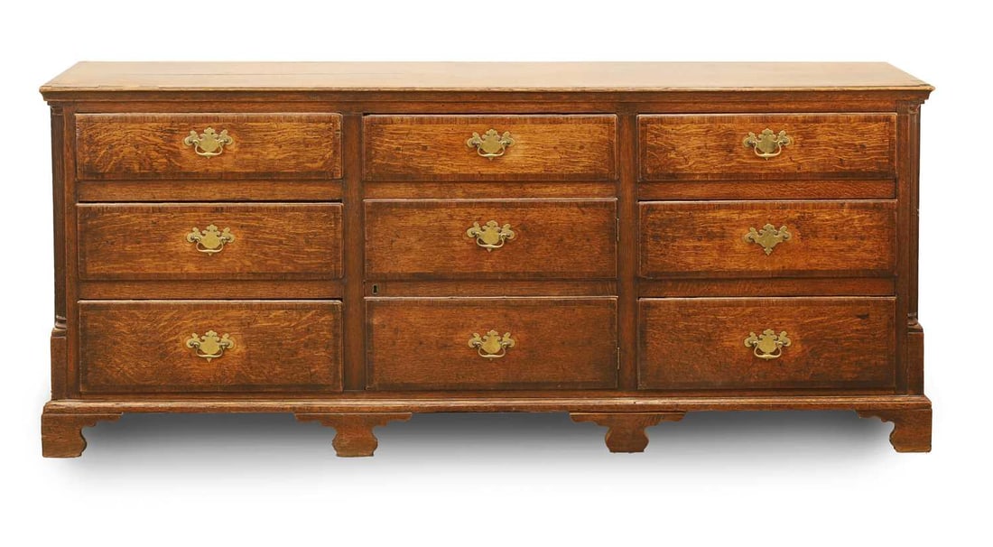 A George III oak multi drawer chest, early 19th century,: A George III oak multi drawer chest, early 19th century, with an arrangement of seven drawers, and a cupboard door disguised as drawers, all with swan neck handles 197cm wide, 45.5cm deep, 86cm high