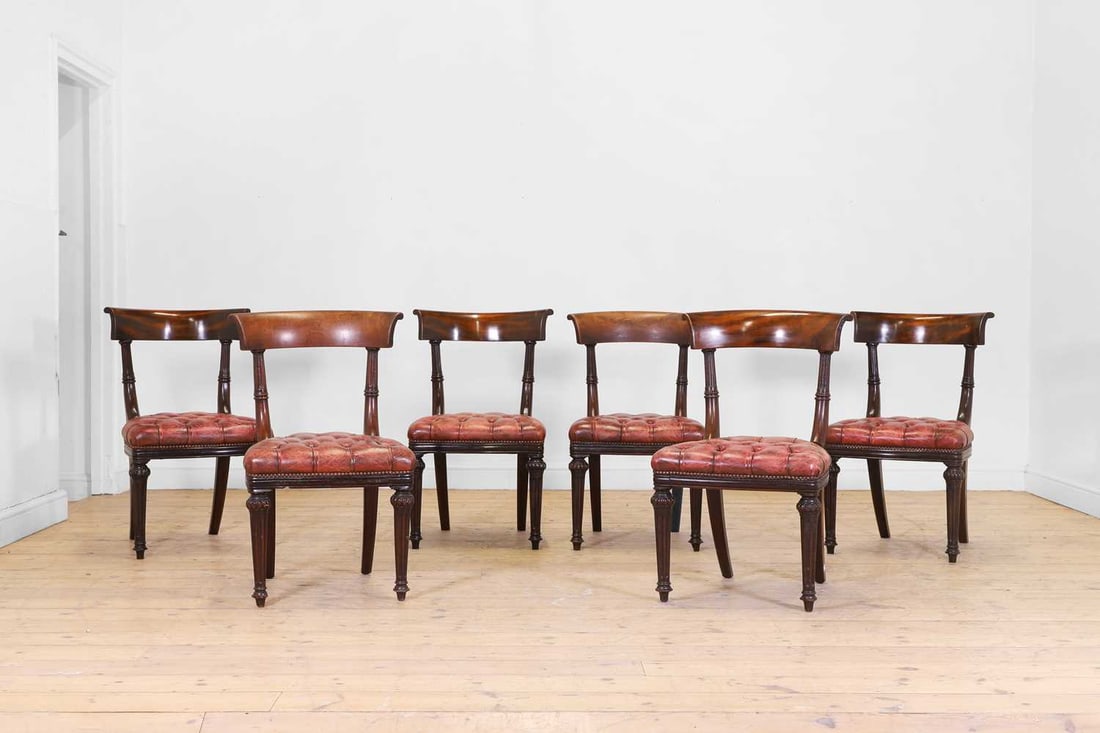 A set of six mahogany and buttoned-leather dining chairs, 19th century and later,: A set of six mahogany and buttoned-leather dining chairs, 19th century and later, each with a curved back and reeded supports above a studded seat, raised on tapering fluted legs, one stamped with