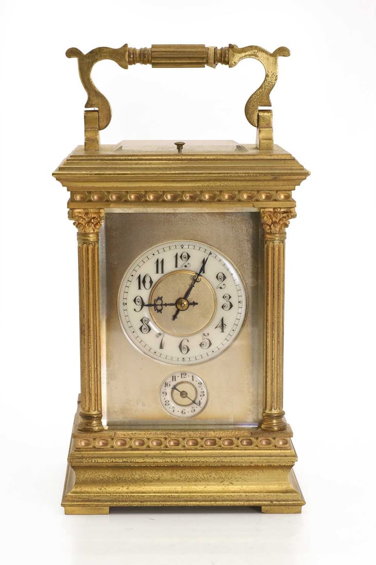 A gilt metal carriage alarm clock, by Tiffany & Co,: A gilt metal carriage alarm clock, by Tiffany & Co, the eight-day movement with gong strike and repeat, the white enamel dial with black Arabic numerals, signed Tiffany & Co. 11cm wide, 16.5cm hig