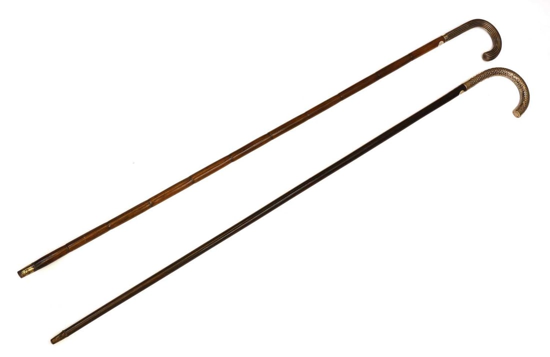Two silver-mounted walking canes, circa 1900-10,: Two silver-mounted walking canes, circa 1900-10, with crook handles, one hammered and stamped 800 standard, with an ebony shaft, the other with a Partridge wood shaft 93cm and 95cm long 2 Condition Re