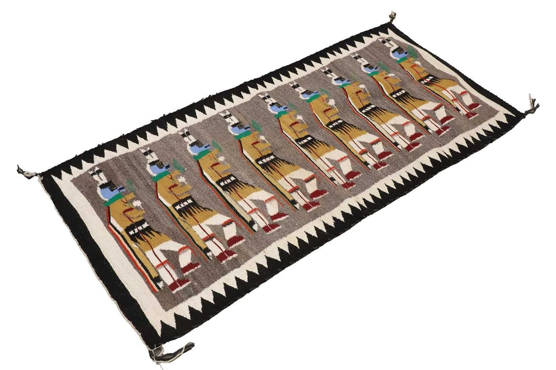 A Native American Navajo wool rug, second half of the 20th century,: A Native American Navajo wool rug, second half of the 20th century, decorated with repeating Yei Be Chei dancers to a grey ground 148 x 69cm Provenance: Acquired in 1981 from Kayenta Trading Post, Ari