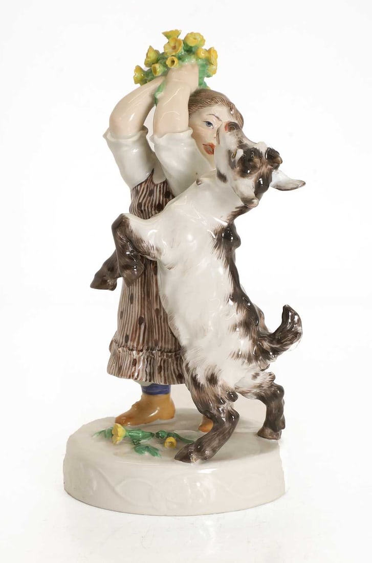 A Meissen figure 'Girl with Goat', circa 1905,: A Meissen figure 'Girl with Goat', circa 1905, modelled by Erich Hoesel, depicting a girl holding flowers away from a hungry goat, model number 114, with painted blue crossed swords mark to the base 1