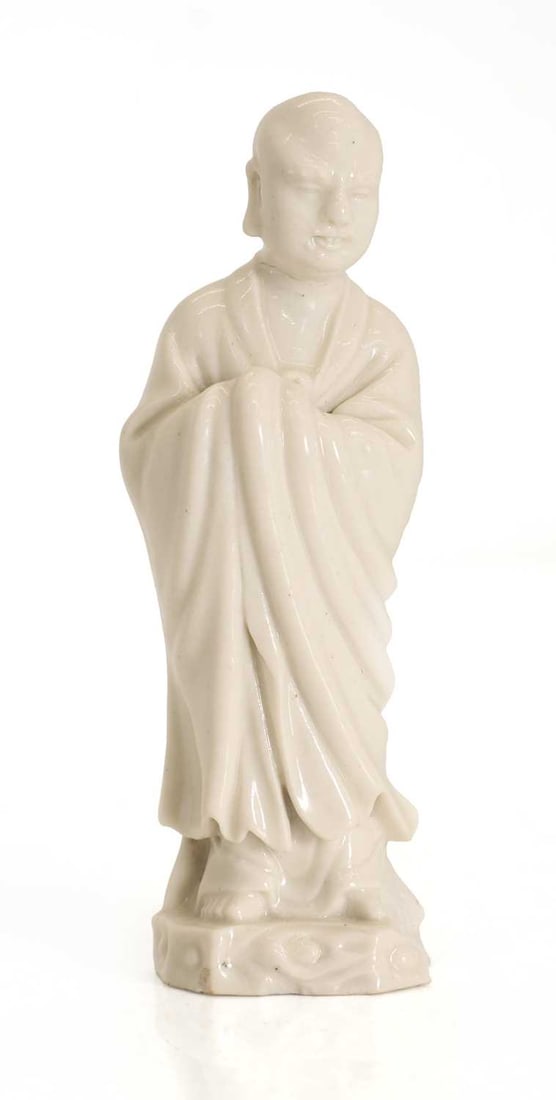 A blanc de Chine figure of a luohan, 20th century,: A blanc de Chine figure of a luohan, 20th century, modelled standing on rocky base 13.5cm high