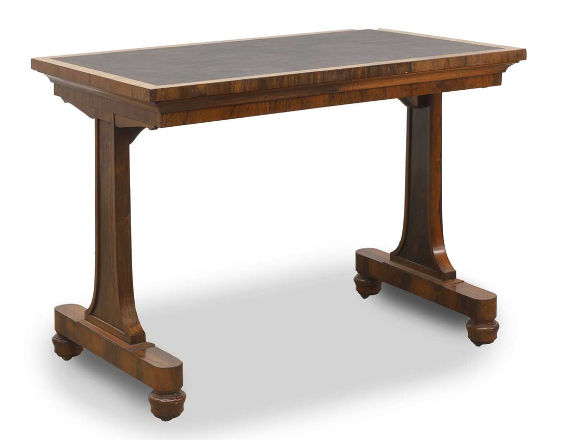 A William IV rosewood writing table, c.1830,: A William IV rosewood writing table, c.1830, with a black leather top over twin shaped supports on bun feet and castors