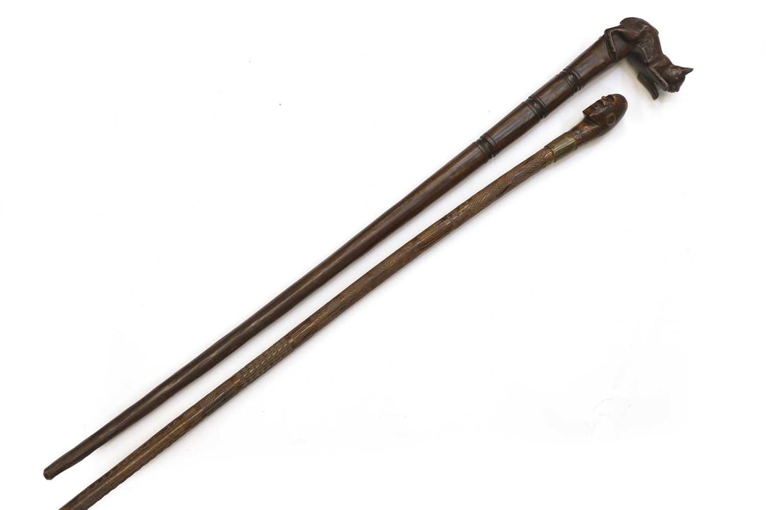A tribal carved walking stick and another carved with a cat, early 20th century,: A tribal carved walking stick and another carved with a cat, early 20th century, one profusely carved to the shade, the other with turned bands, 89cm and 94.5cm long 2 Condition Report: Fair, worn
