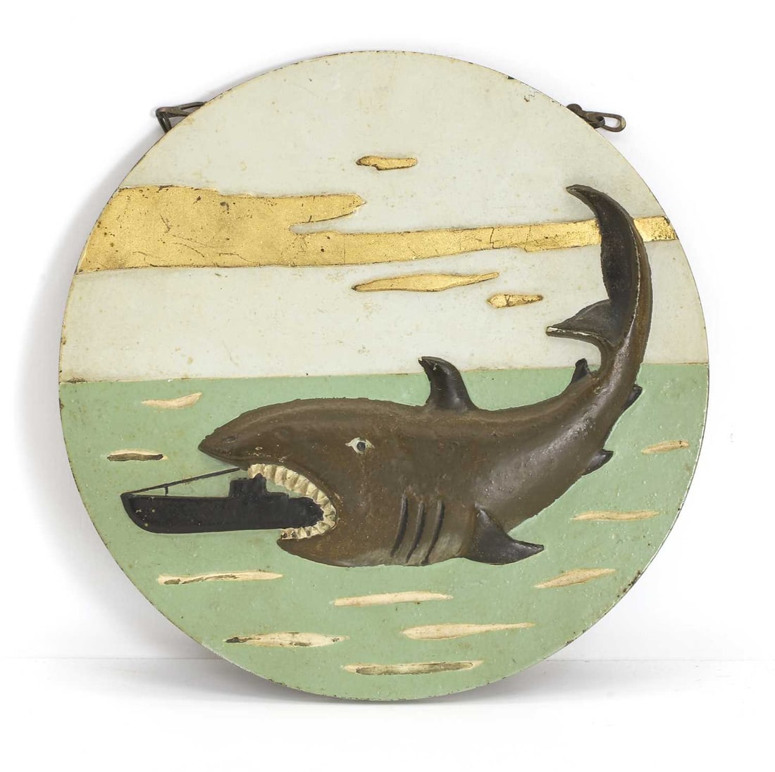 A WWII painted bronze circular plaque, circa 1940s,: A WWII painted bronze circular plaque, circa 1940s, cast in low relief with a shark eating a submarine, with ring suspension 19.5cm diameter Condition Report: Fair overall. The ring suspensions added