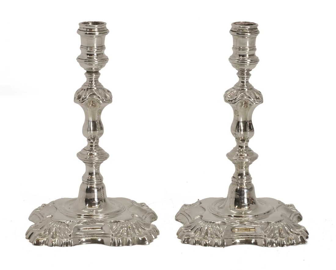 A pair of small silver candlesticks,: A pair of small silver candlesticks, by Garrard & Co Ltd, London, 1934, the turned style centre column, with floral detailing, the scalloped base with crest of hands holding a crown 12.8cm high, 1