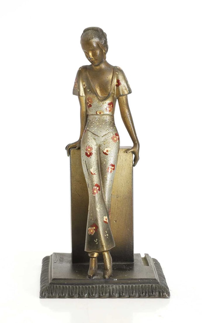 An Austrian Art Deco spelter table lighter, after Lorenzl,: An Austrian Art Deco spelter table lighter, after Lorenzl, modelled as a lady, cold-painted with a floral blouse and trousers, signed Lorenzl in the cast and 'Made in Austria and 'ANR' 10cm wide and