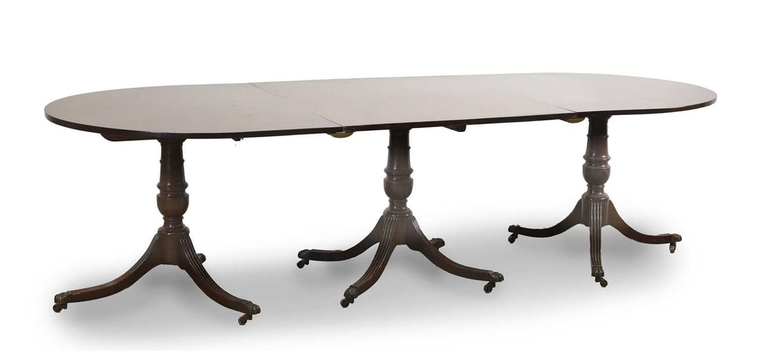 A mahogany triple pillar dining table, 19th century,: A mahogany triple pillar dining table, 19th century, in three sections, with demi lune tilt top ends, over reeded, splayed tripod supports, the centre with four legs, upon brass paw castors 113cm