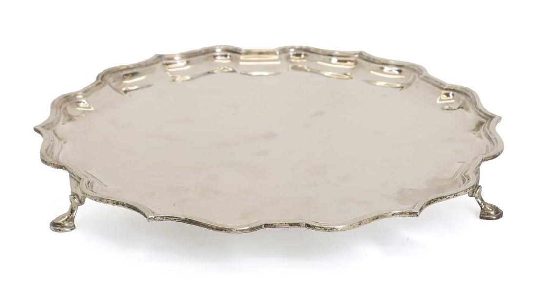 A silver salver,: A silver salver, by Elkington & Co Ltd, Birmingham, 1946, with a scalloped edge and terminating on hoof feet 36.5cm wide, 42.3ozt