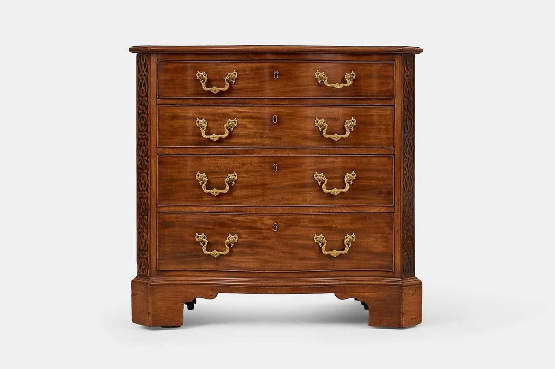 A George III mahogany serpentine chest of drawers, circa 1760,: A George III mahogany serpentine chest of drawers, circa 1760, in the 'Chinese Chippendale' taste, the moulded top above four long graduated drawers, flanked on either side by blind fret canted corner
