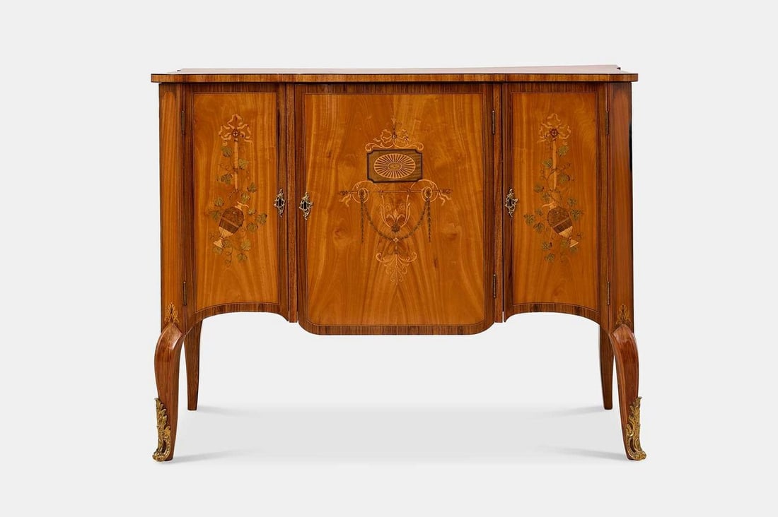 A George III satinwood, tulipwood and harewood marquetry commode, circa 1780, in the manner of: A George III satinwood, tulipwood and harewood marquetry commode, circa 1780, in the manner of Christopher Fuhrlohg, of breakfront outline, the crossbanded and strung top inlaid with a central flower 