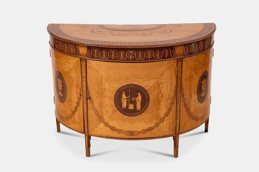 A George III satinwood, harewood and marquetry commode attributed to Ince & Mayhew, circa 1785,: A George III satinwood, harewood and marquetry commode attributed to Ince & Mayhew, circa 1785, of demilune outline, the crossbanded top decorated with paterae, anthemia, foliate, ribbon and drapery d