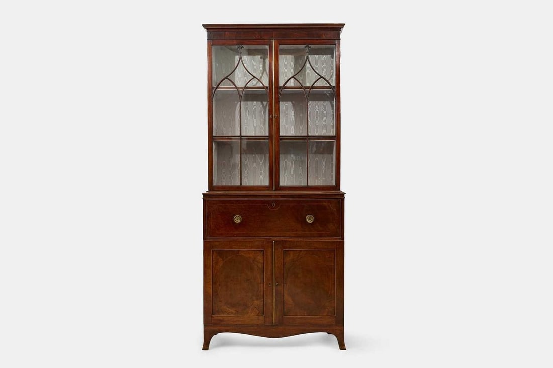 A George III mahogany secretaire bookcase, circa 1780,: A George III mahogany secretaire bookcase, circa 1780, the upper section with a pair of astragal-glazed doors enclosing a shelved interior, above a secretaire drawer with an inset leather skiver and a