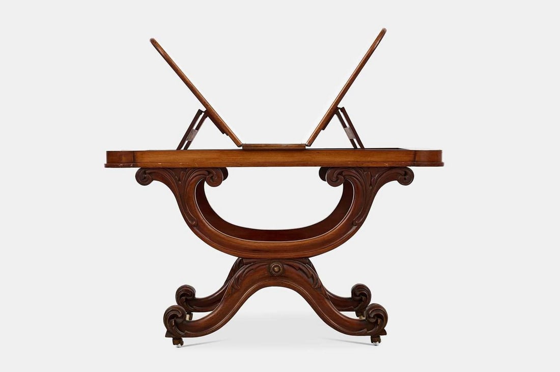 A William IV mahogany folio stand, circa 1835,: A William IV mahogany folio stand, circa 1835, the ratchet top raised on a scrolling 'X'-frame, terminating in castors (90cm wide, 50cm deep, 54cm high ) Provenance:: The collection of Simon Timothy B
