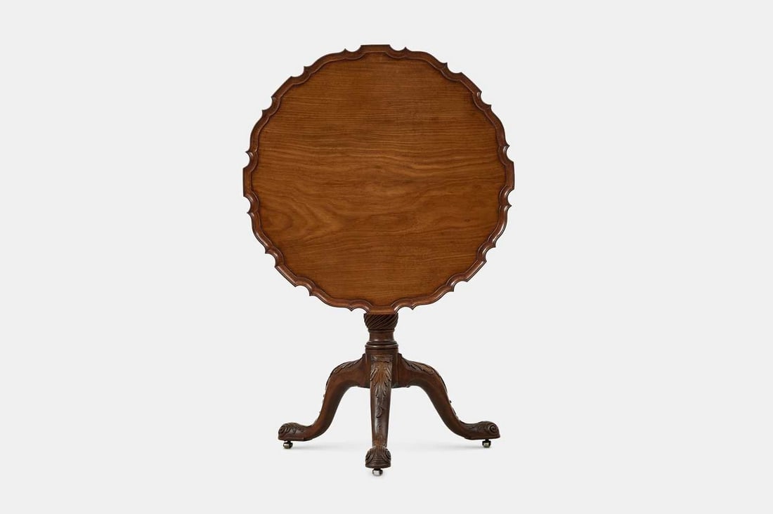 A George II mahogany tripod table, 18th century and later, possibly Irish,: A George II mahogany tripod table, 18th century and later, possibly Irish, fitted with a birdcage mechanism, with a pie-crust top over a wrythen column, terminating in acanthus-carved outscrolling leg