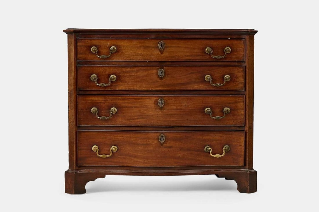 A George III mahogany dressing chest, third quarter of the 18th century,: A George III mahogany dressing chest, third quarter of the 18th century, of serpentine outline, the top drawer fitted with a baize-lined slide over an arrangement of pigeonholes and storage compartmen