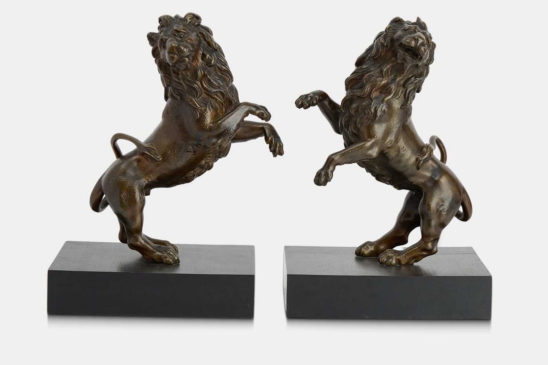 A pair of bronze lion rampant sculptures, first quarter of the 18th century, Northern European,: A pair of bronze lion rampant sculptures, first quarter of the 18th century, Northern European, modelled in an upright rearing position, each mounted on an ebonised wooden base (lions 21cm wide, 9cm d