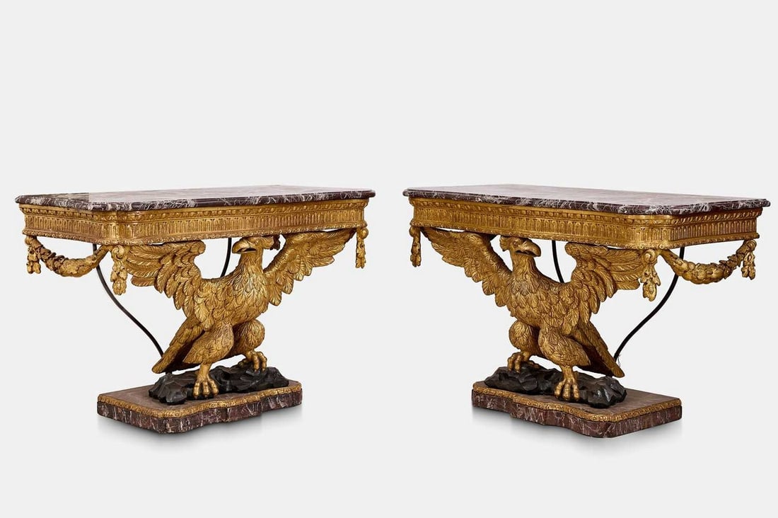 A pair of George II-style carved giltwood eagle console tables, late 19th/early 20th century, in the: A pair of George II-style carved giltwood eagle console tables, late 19th/early 20th century, in the manner of William Kent, each with a serpentine rouge marble top above an egg-and-dart moulded friez