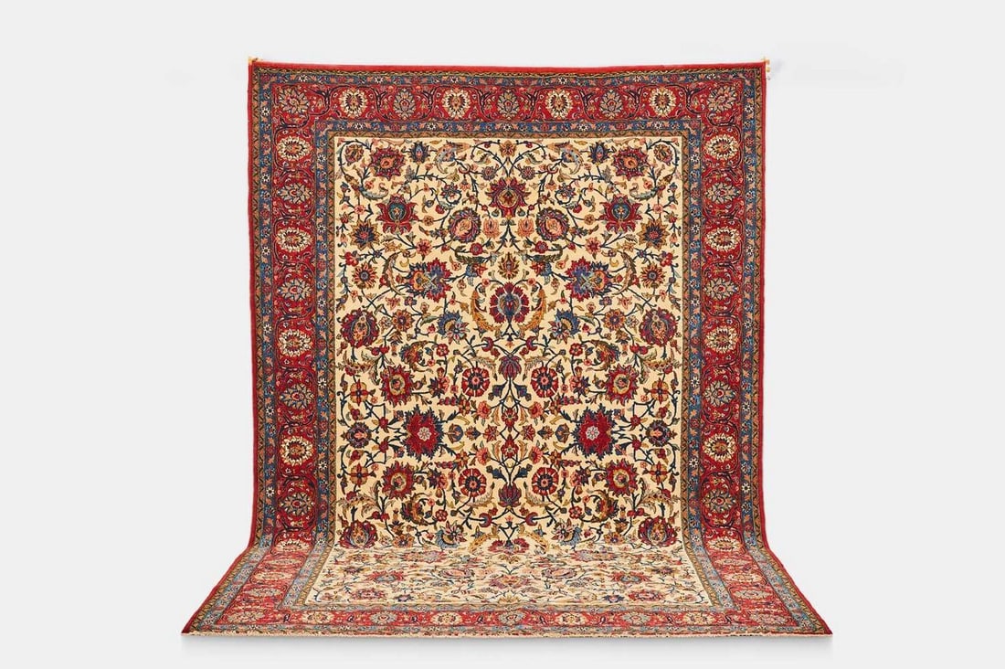 A Qum wool carpet, circa 1930, Persian,: A Qum wool carpet, circa 1930, Persian, with a central ivory field, woven throughout with repeating foliate motifs (346 x 236cm) Condition Report: Please note: although we try to reproduce colours as 